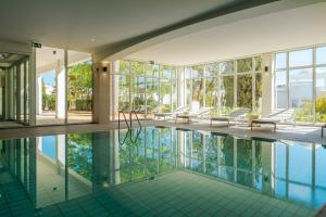 an indoor pool in a house with windows and chairs at Hapimag Resort Albufeira in Albufeira
