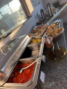 a buffet with several trays of food on a counter at Aqui Hotel in Patos de Minas