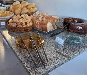 a counter with bread and pastries on a table at Aqui Hotel in Patos de Minas +1 photo