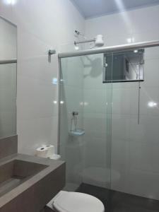 a bathroom with a toilet and a glass shower at Aqui Hotel in Patos de Minas