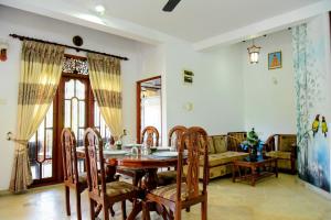 a dining room with a table and chairs and a couch at Accoma Villa in Hikkaduwa