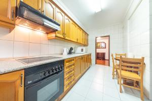 una cucina con armadi in legno e forno a piano cottura nero di Esmael Apartment By Mth a Funchal