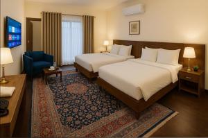 a hotel room with two beds and a blue chair at Relax Lodge Family Guest House in Islamabad