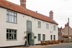 a white building with tables and chairs in front of it at The Three Swallows Cley in Cley next the Sea +44 photos