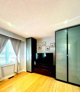 uma sala de estar com uma televisão de ecrã plano e uma janela grande em Cozy Queen room with Shared Bath near Seneca Finch 404 em Toronto