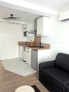 una cocina con armarios blancos y un sofá negro en Le Nid des piétons - Hyper Centre, en Valence