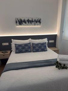 Alojamientos Dima Costa في لاريدو: غرفة نوم مع سرير ووسائد زرقاء وبيضاء