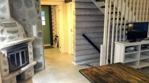 un soggiorno con una scala e un camino di Vuokatin Lomakämpät a Sotkamo