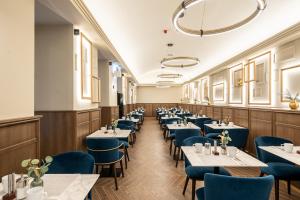 a dining room with tables and blue chairs at BasiliQ Hotel in Budapest