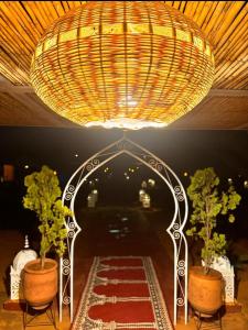a large chandelier hanging from a ceiling with two plants at Desert Pearl Camp in Merzouga