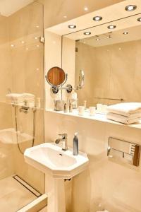 um banheiro branco com pia e chuveiro em Strandhotel Strande em Strande