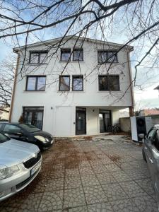 Farska apartman priamo v centre Nitry في نيترا: بيت ابيض وسيارتين متوقفتين امامه