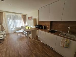 a kitchen with white cabinets and a table with chairs at Sunlit Forest Suite in Borovets