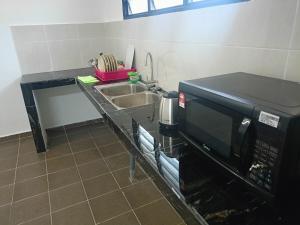 a kitchen counter with a microwave and a sink at Ipoh budget house in Ipoh