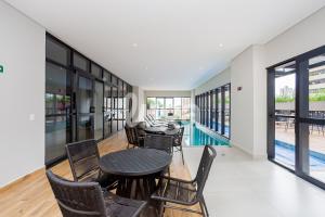 a dining room with a table and chairs and a pool at Studio Resort Piscina Aquecida GYM Bem localizado in Curitiba