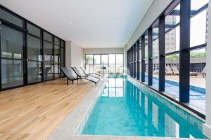 a swimming pool in a house with glass windows at Studio Resort Piscina Aquecida GYM Bem localizado in Curitiba