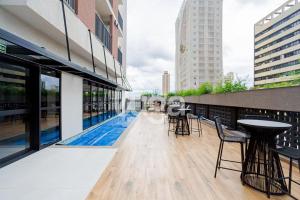 a balcony with tables and chairs on a building at Studio Resort Heated Pool GYM Best Location in Curitiba