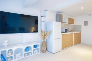 cocina blanca con nevera y encimera en Eros Suite, Greek-style apartment with Jacuzzi, en Brignoles