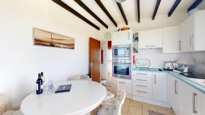 a white kitchen with a white table and chairs at C16 Treverbyn, Riviere Towans in Hayle +2 photos
