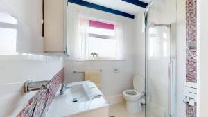 a bathroom with a sink and a toilet and a window at C16 Treverbyn, Riviere Towans in Hayle