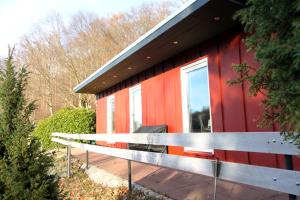 a red house with a bench in front of it at Komfortabler Bungalow Am Schlosswald mit privater Sauna&Terrasse - Wernigerode Harz in Wernigerode