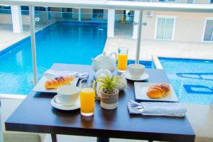 Royal Ambassador Hotel في Harbel: طاولة عليها طعام للإفطار وعصير البرتقال