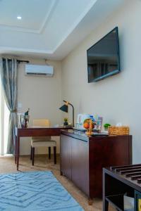 Royal Ambassador Hotel في Harbel: غرفة معيشة مع مكتب وتلفزيون على الحائط