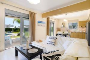 a living room with a white couch and a table at Kamari Beach in Lartos