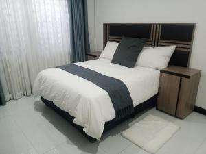 a bedroom with a bed with a black and white comforter at LOMS Furnished Apartment - Luxurious Modern House near KKI Airport in Kenneth Kaunda International Airport