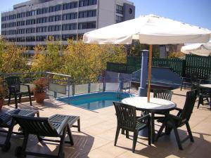 une table et des chaises avec un parasol à côté d'une piscine dans l'établissement San lorenzo apart, à Mendoza
