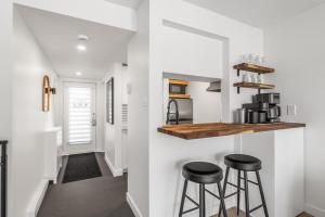 a kitchen with white walls and two stools in a room at Hameau 26-43 Studio in Stoneham +13 photos