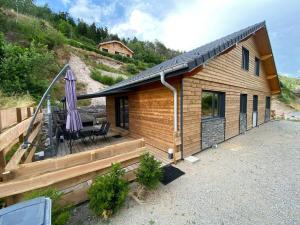 a small house with a patio and an umbrella at Chalets Capucine ou Clochette 5P - SPA Privatif in Rochesson