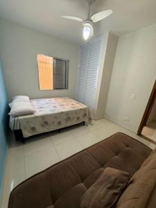 een slaapkamer met een bed en een bank erin bij Casa Praia Bertioga in Bertioga