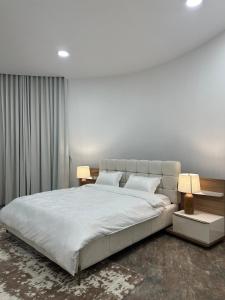 a bedroom with a large white bed with two lamps at Ebreez Heaven in Wāsiţ +19 photos