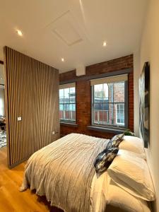 una camera da letto con un letto e due finestre di Stylish City Penthouse Getaway a Nottingham