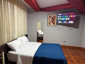 タクナにあるHostal Williamsのベッドと壁にテレビが掛かった寝室