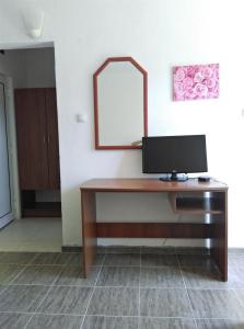 a desk with a monitor and a mirror on a wall at Guest House Villa Rose in Primorsko