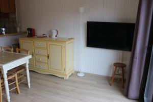 a room with a yellow cabinet and a tv on a wall at Appartement Peyragudes les Agudes in Gouaux-de-Larboust