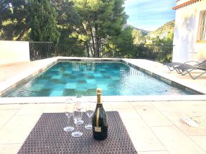 een fles wijn en wijnglazen op een tafel naast een zwembad bij Global Immo 9101 Pacheco Beach in Roses