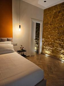 a bedroom with a bed and a stone wall at Corte Atenea Guest House Experience & Spa in Agrigento