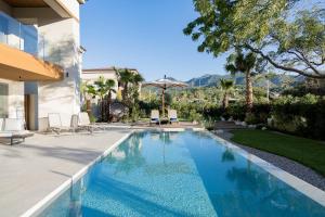 a swimming pool in a yard with chairs and a house at Almyros Beach in Acharavi