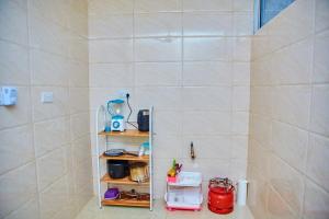 Un baño con un estante en la esquina de una habitación. en Kilimani Apartment 1, en Migombani