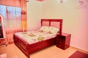 1 dormitorio con cama con marco de madera y ventana en Kilimani Apartment 1, en Migombani