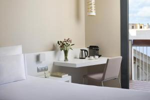 a white room with a table and a vase with flowers at NH Castellón Mindoro in Castellón de la Plana