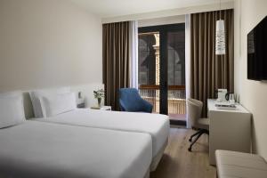 a hotel room with a bed and a desk and a window at NH Castellón Mindoro in Castellón de la Plana