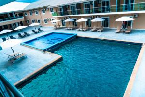a swimming pool in front of a hotel with chairs and umbrellas at Royal Ambassador Hotel in Harbel