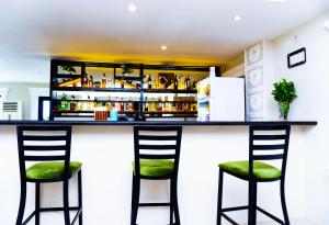 Royal Ambassador Hotel في Harbel: بار مع اثنين من المقاعد أمام منضدة +صورتان