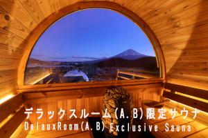 グランファーム富士河口湖 Granfarm Fujikawaguchiko في فوجيكاواجوتشيكو: نافذة في مبنى خشبي تطل على منظر جبلي