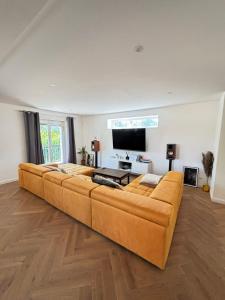 Soh Rent Maison - Villa Piscine Proche Strasbourg - TV - Wifi - Parking في Lampertheim: أريكة كبيرة في غرفة معيشة مع تلفزيون