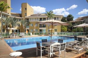 una piscina con mesa y sillas y una sombrilla en The Sun Full Condominiun, en Brasilia